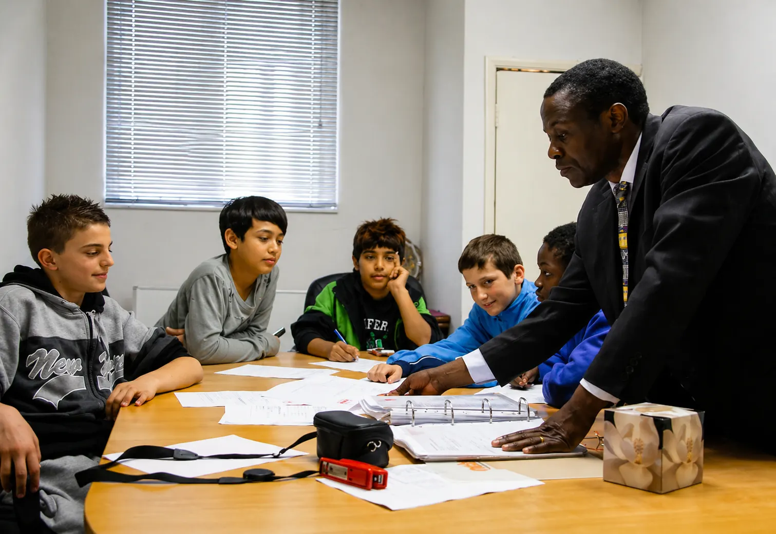 A mentor leading a discussion group with young people around a table.